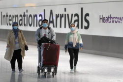 Khách du lịch đeo khẩu trang khi di chuyển tại sân bay Heathrow, Anh.